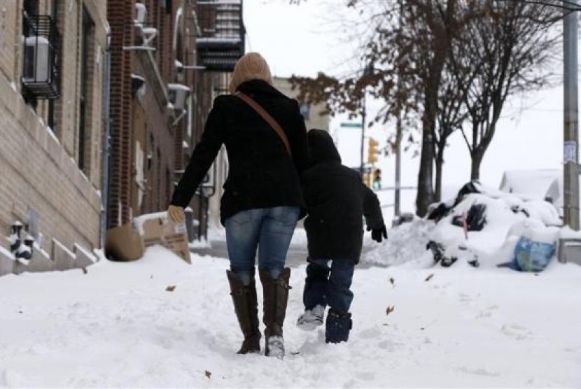 A woman and her son make their way up a snow covered sidewalk in the South Bronx section of New York City, January 3, 2014.