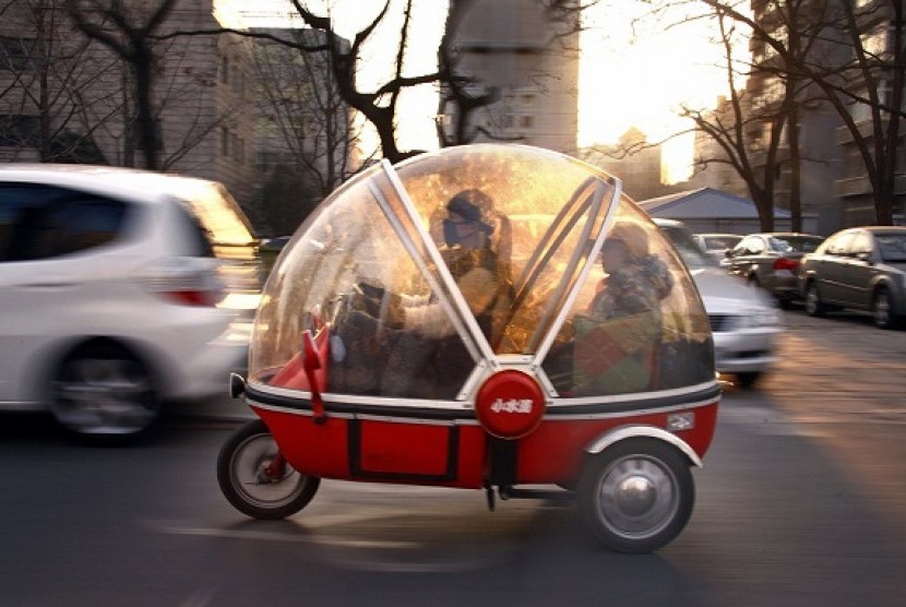 A woman and her son sit inside the capsule of an electric tricycle as they drive along a main road in central Beijing March 15, 2012.  