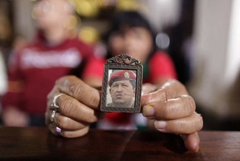 A woman holds an image of Venezuela's President Hugo Chavez as people gather to pray for him at a church in Caracas, Venezuela, Monday, Dec. 31, 2012.   