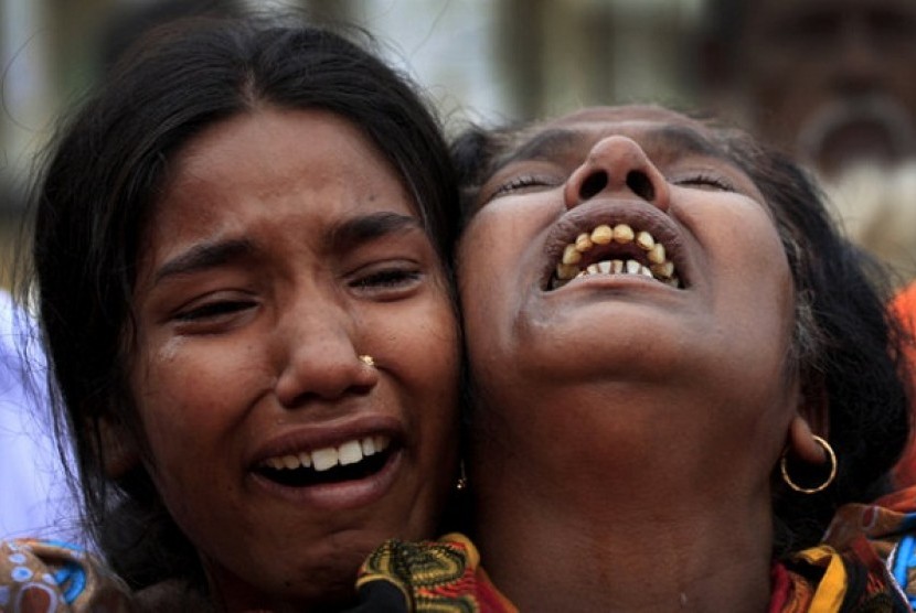 A woman is comforted as she grieves after identifying the body of her daughter, a victim of the garment factory collapse, Sunday, May 5, 2013 in Savar, near Dhaka, Bangladesh. 