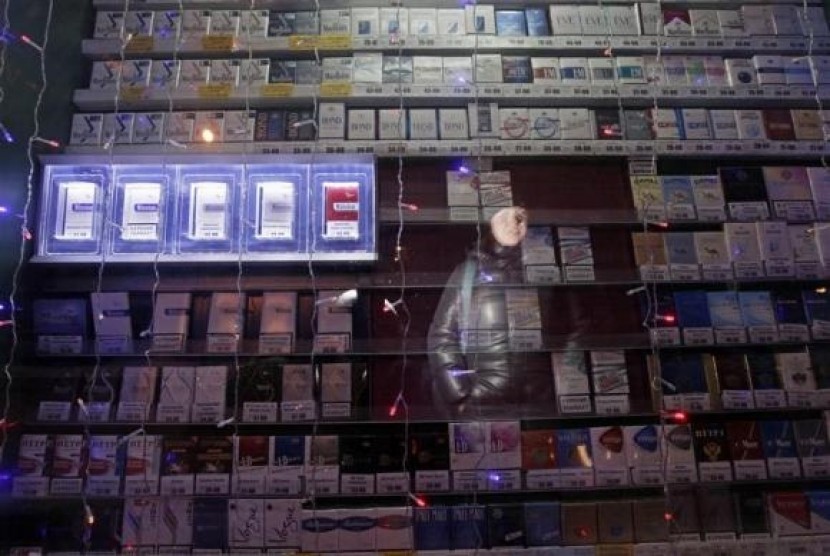 A woman is reflected in a window displaying packs of cigarettes on a street in Russia's Siberian city of Krasnoyarsk January 24, 2013.