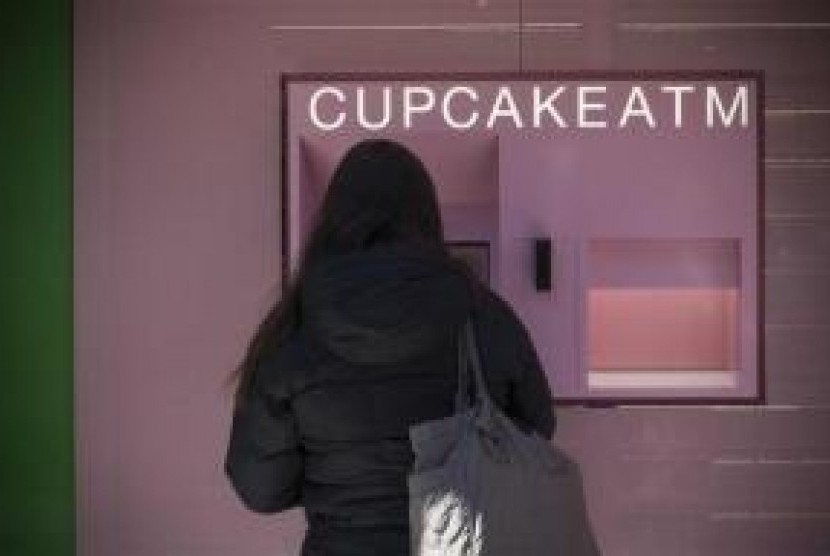 A woman makes a purchase from the Cupcake ''ATM'' at Sprinkles Cupcake Bakery in New York City's Upper East Side in Manhattan, March 26, 2014.