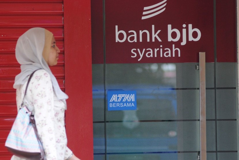 A woman passes Bank Syariah BJB's automatic teller machine (ATM). 