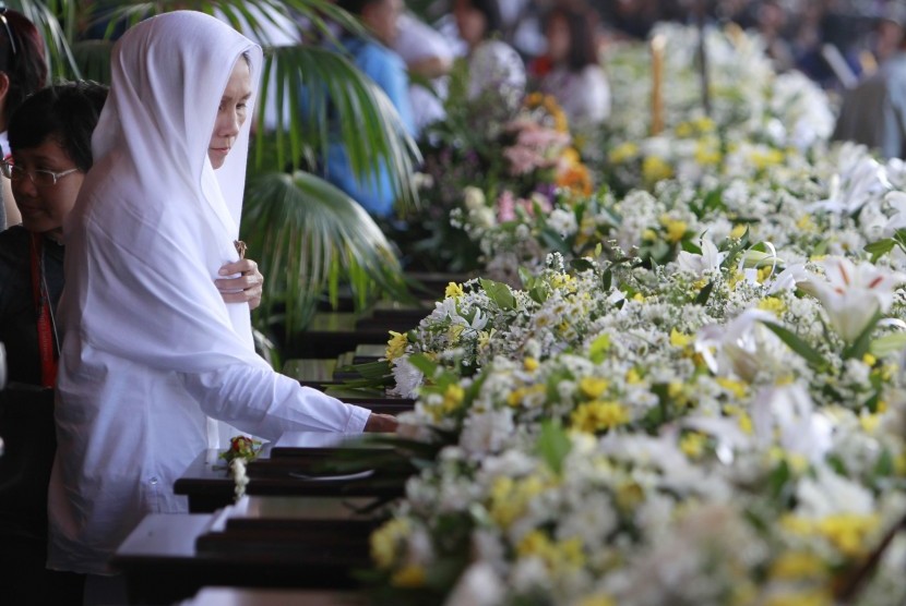 A woman places a hand on the coffin of one of the victims of a Russian Sukhoi Superjet 100 plane that crashed on Salak Mountain, during a ceremony at Halim Perdanakusuma airport in Jakarta on Wednesday. The remains of all 45 victims of the crash were officially handed over to their families.