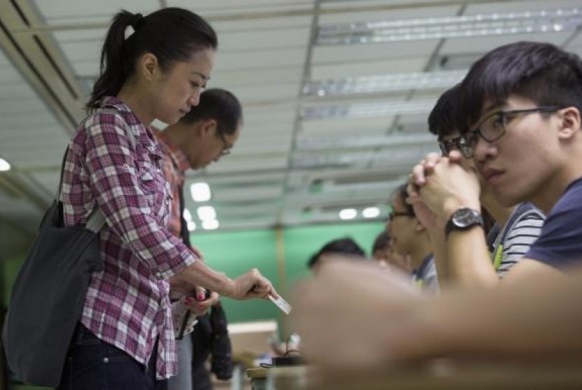 A woman presents her ID card to a poll assistant during a civil referendum held by the Occupy Central organisers at polling station in Hong Kong June 22, 2014.