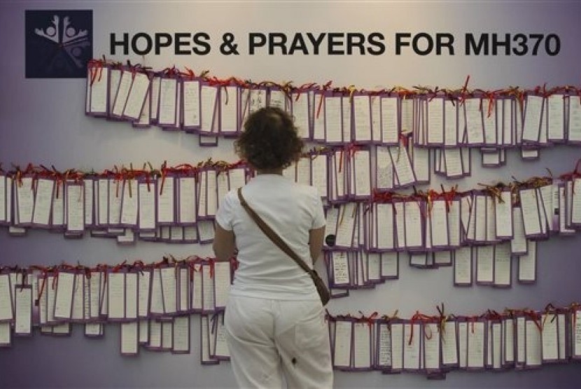 A woman read message cards tied up for passengers aboard a missing Malaysia Airlines plane, at a shopping mall in Kuala Lumpur, Malaysia, Monday, March 24, 2014. A