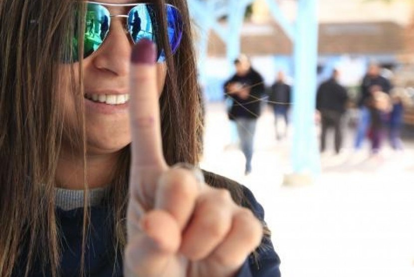 A woman shows her ink-stained finger after casting her vote at a polling station in Tunis December 21, 2014.