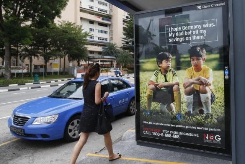 A woman walks past a World Cup anti-gambling advertisement at a taxi stand in Singapore July 9, 2014.