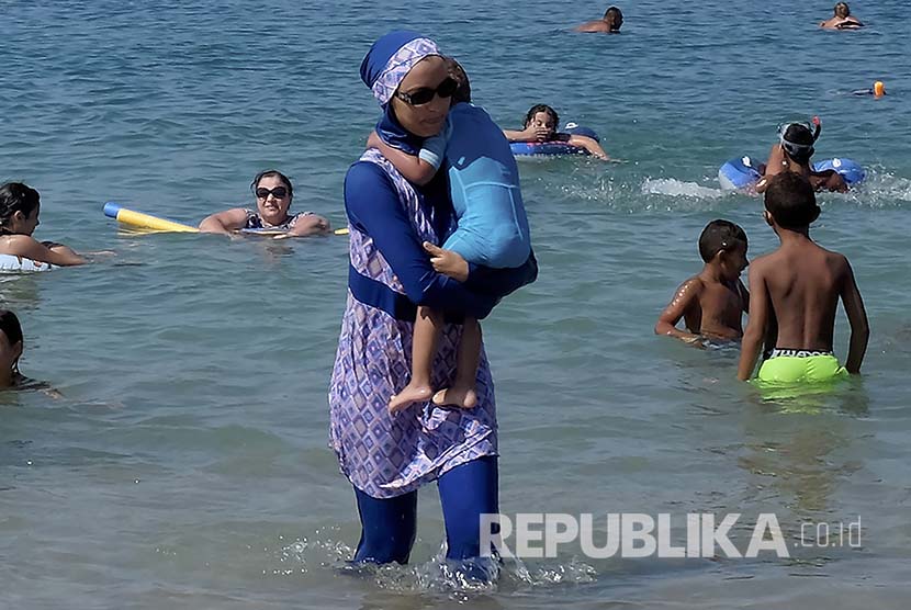 Malaysia Kutuk Pengesahan RUU 'Diskriminasi' Muslim Prancis. Seorang wanita Muslim mengenakan pakaian renang Muslim atau Burkini di sebuah pantai di Marseille, Prancis.