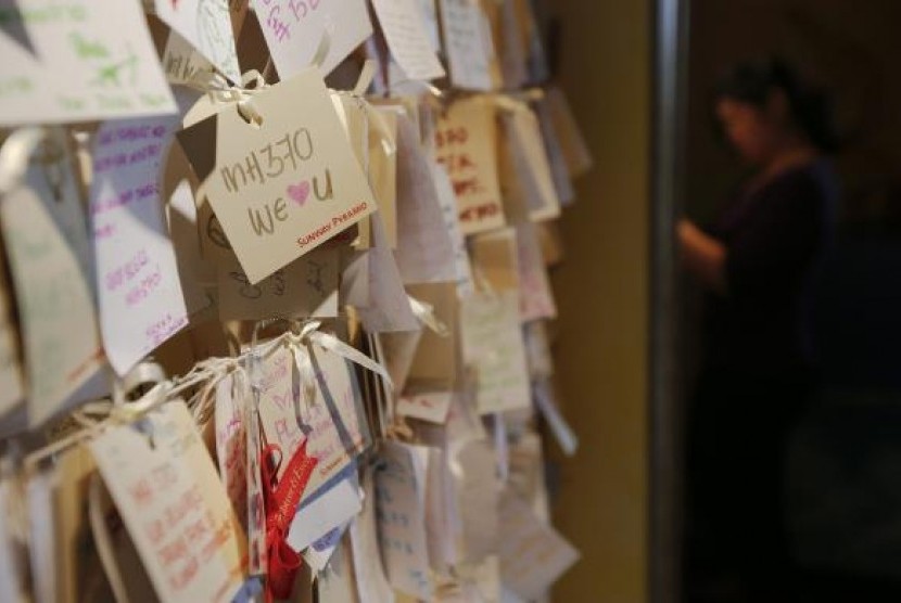 A woman writes another message of hope and support for the passengers of the missing Malaysia Airlines MH370 at a mall outside Kuala Lumpur March 22, 2014. 