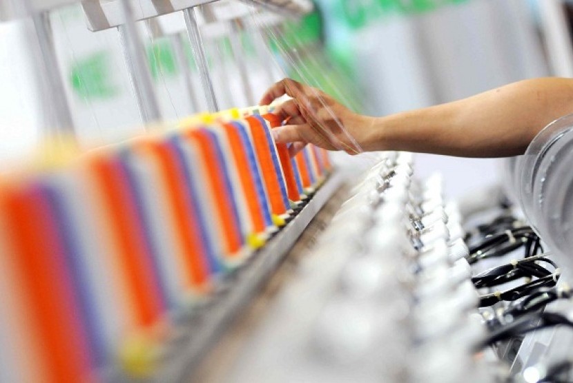 A worker checks the threads in embroidery machine at an exhibition in Jakarta.  