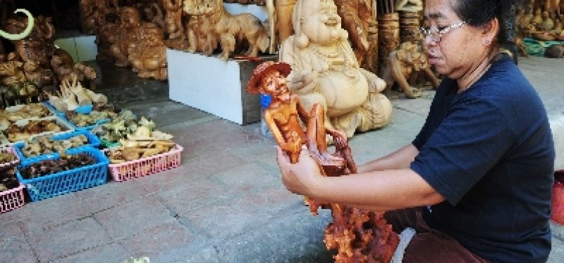 A worker sandpapers a wooden statute in Ubud, Bali (illustration).