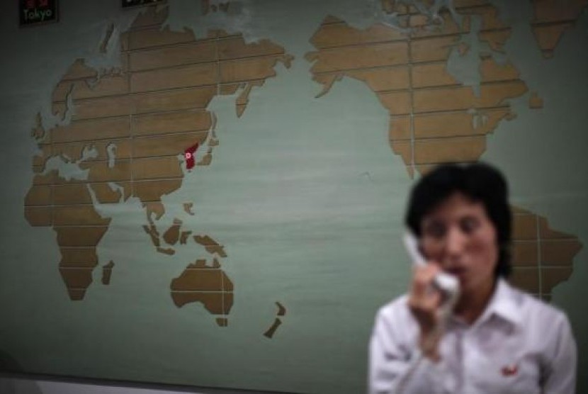 A world map, with the Korea peninsula marked in red, is seen as a hotel receptionist talks on the phone in Rason city, northeast of Pyongyang, August 29, 2011.