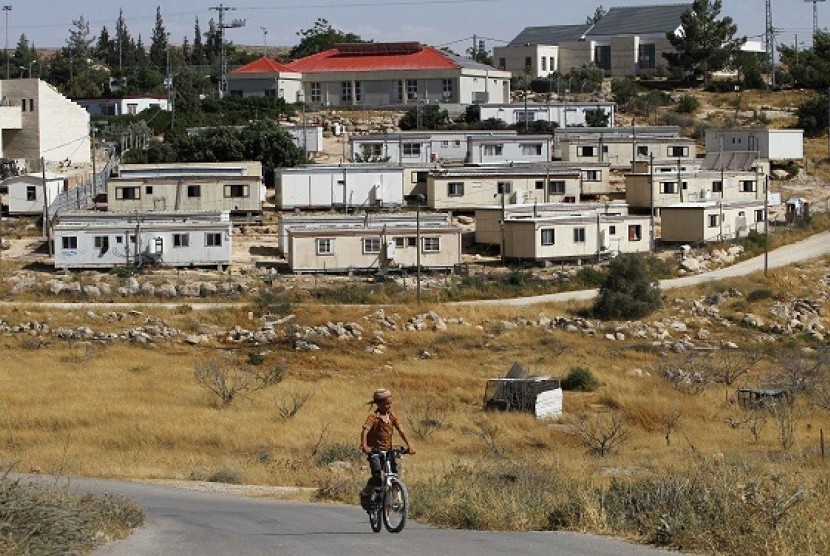 A young Jewish settler rides a bicycle in front of the West Bank settlement of Susiya June 24, 2012. Susiya the settlement enjoys well-watered lawns, humming electricity, and the protection of a mighty state. One rocky hill away, Susiya the Palestinian vil