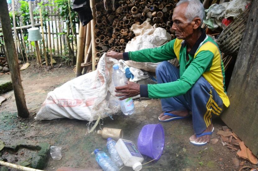Abah Sarwan sedang mengumpulkan botol plastik hasil memulung.