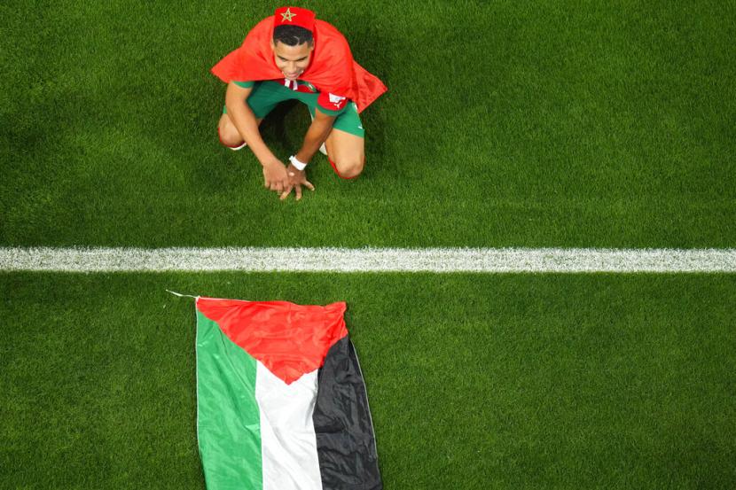  Abdelhamid Sabiri dari Maroko merayakan, duduk di dekat bendera Palestina, setelah pertandingan sepak bola babak 16 besar Piala Dunia antara Maroko dan Spanyol, di Stadion Education City di Al Rayyan, Qatar, Selasa, 6 Desember 2022.