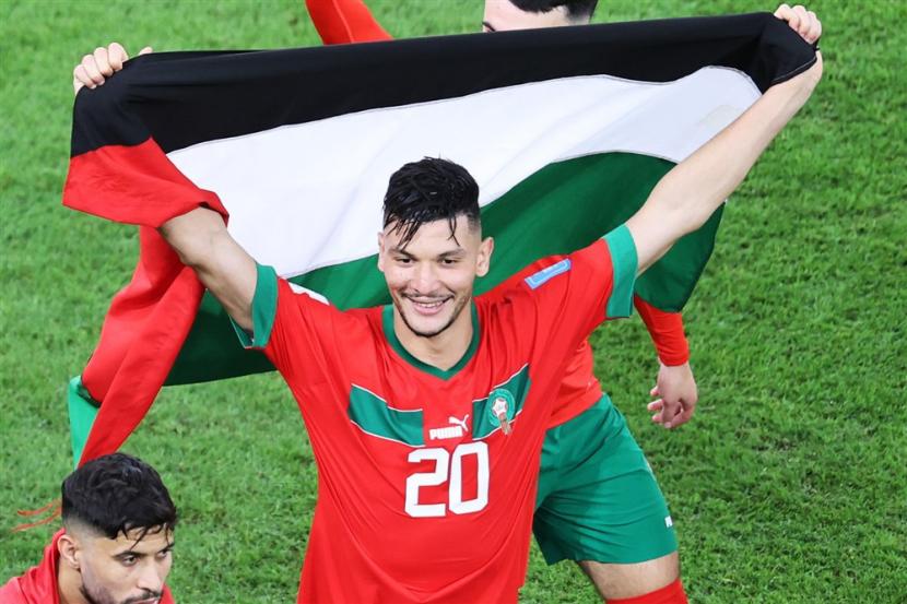  Achraf Dari Maroko merayakan dengan Bendera Palestina setelah pertandingan sepak bola perempat final Piala Dunia FIFA 2022 antara Maroko dan Portugal di Stadion Al Thumama di Doha, Qatar, Sabtu (10/12). Pasukan Israel Pukuli Warga Palestina Rayakan Kemenangan Maroko Atas Portugal