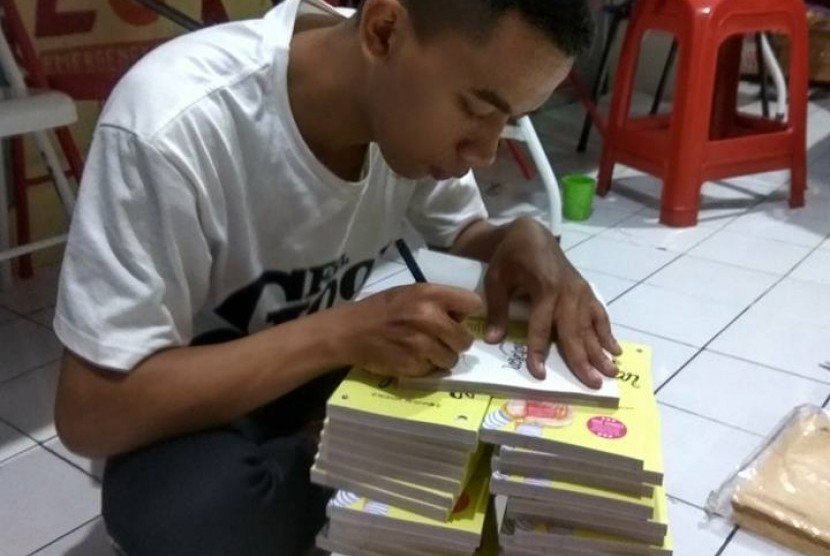 Ade Nurpalah menandatangani bukunya.
