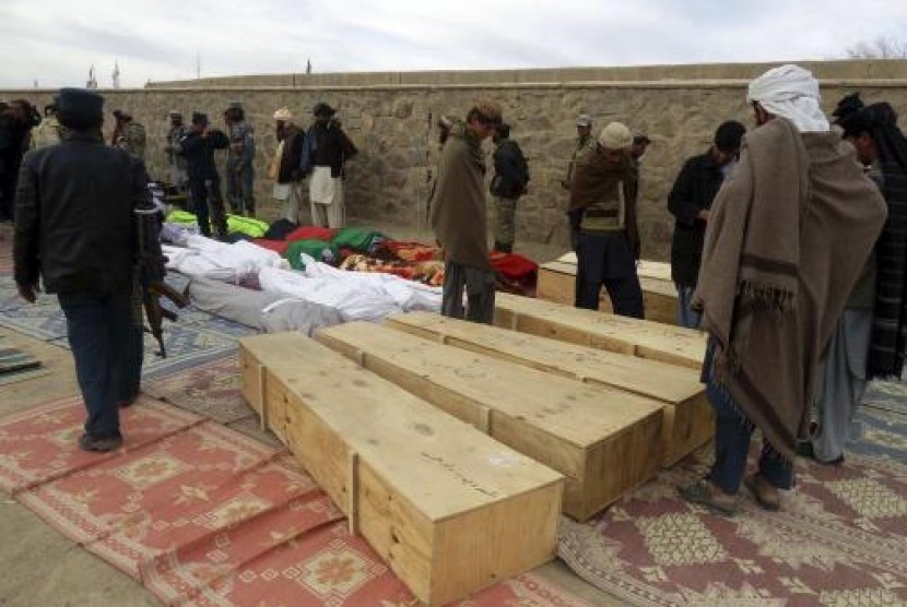 Afghan men gather around the bodies of victims of Sunday's suicide attack at a volleyball match in Yahya Khail district, Paktika province, November 24, 2014.