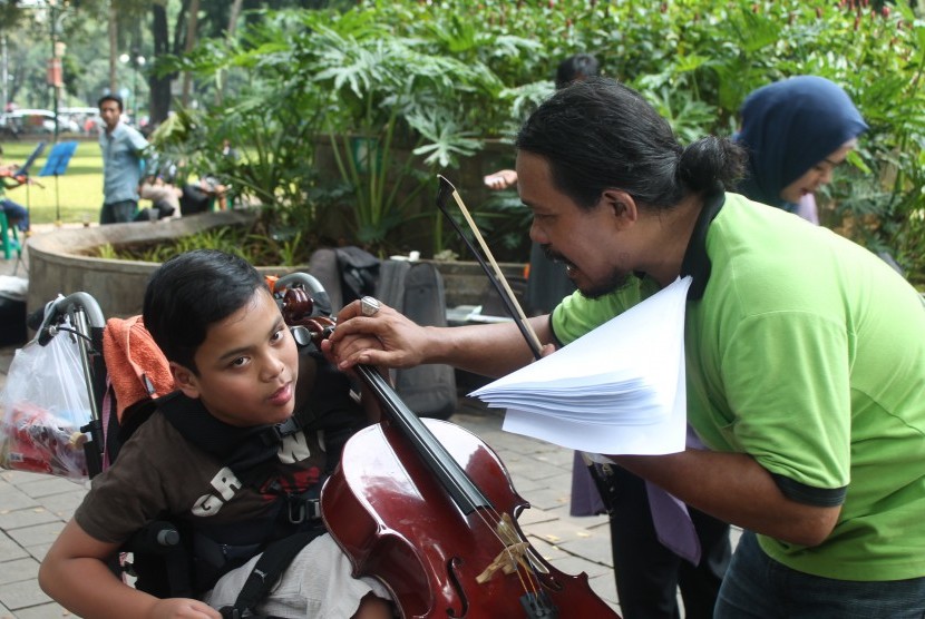 Ages Dwi Harso, pendiri komunitas Taman Suropati Chambers mengajarkan seorang anak bermain Cello