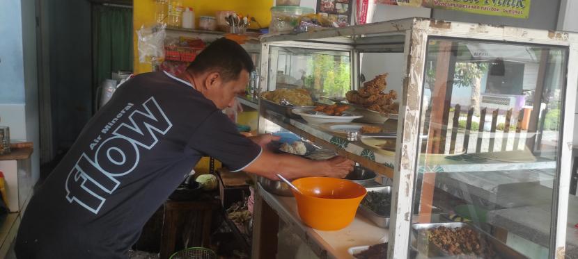  Ahmad Gayuh, pemilik warung makan, sedang mengambilkan lauk untuk pelanggan
