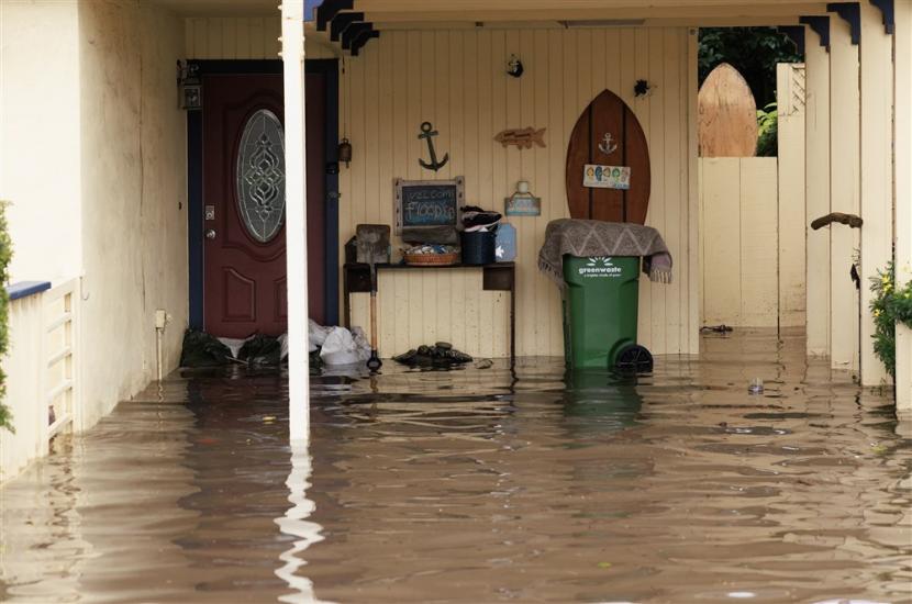  Air banjir menghantam pintu depan sebuah rumah yang terbungkus pasir di sepanjang Aptos Beach drive di Aptos, California, AS, Sabtu (14/1/2023).Gubernur California Gavin Newsom mengumumkan keadaan darurat akibat badai musim dingin. Banyak kabupaten California berada di bawah peringatan banjir.
