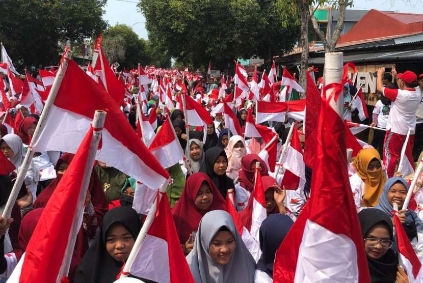 Aksi 1.945 perempuan mengibarkan Bendera Merah Putih setelah sebelumnya dijahit sendiri, Minggu (30/9). Aksi dalam rangkaian Kirab Satu Negeri tersebut diganjar rekor MURI.