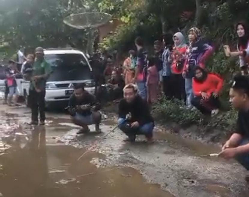 Aksi sejumlah warga memancing di kubangan air di jalan yang kondisinya rusak, wilayah Kecamatan Mekarmukti, Kabupaten Garut, Jawa Barat. 