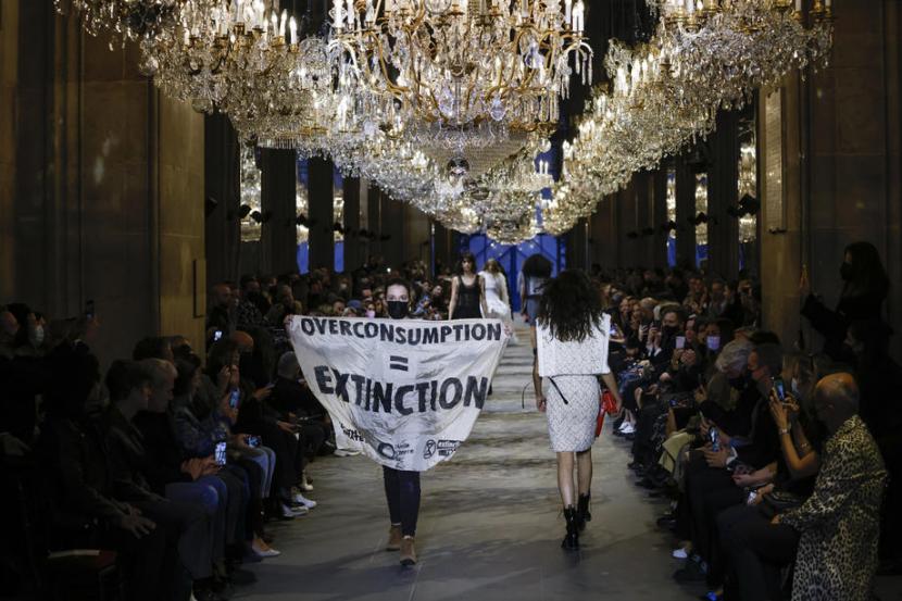 Aktivis Amis de la Terre France Youth for Climate and Extinction Rebellion ikut naik panggung peragaan busana Louis Vuitton di Paris, Prancis, Selasa. Ia membentangkan spanduk di atas catwalk.