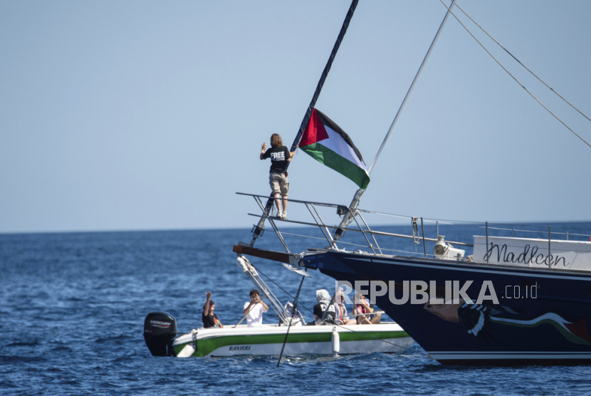 Aktivis iklim Greta Thunberg berdiri di dekat bendera Palestina setelah menaiki kapal Madleen dan sebelum berlayar ke Gaza bersama dengan aktivis Koalisi Armada Kebebasan, berangkat dari pelabuhan Sisilia Catania, Italia, Minggu, 1 Juni 2025.