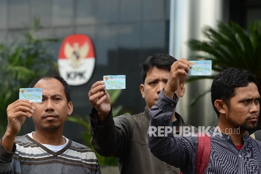 Aktivis Koalisi Masyarakat Sipil menunjukan Kartu Tanda Penduduk (KTP) Elektronik saat melakukan aksi di depan Gedung Komisi Pemberantasan Korupsi (KPK), Jakarta, Ahad (12/3).