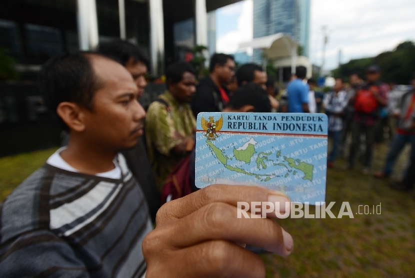 Aktivis Koalisi Masyarakat Sipil menunjukan Kartu Tanda Penduduk (KTP) Elektronik saat melakukan aksi di depan Gedung Komisi Pemberantasan Korupsi (KPK), Jakarta, Ahad (12/3).