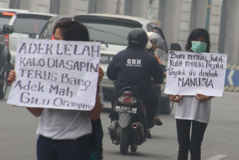 Aktivis lingkungan dari Komunitas Satria Hijau membentangkan poster saat menggelar aksi menolak kabut asap di Medan, Sumatera Utara, Jumat (23/10). 