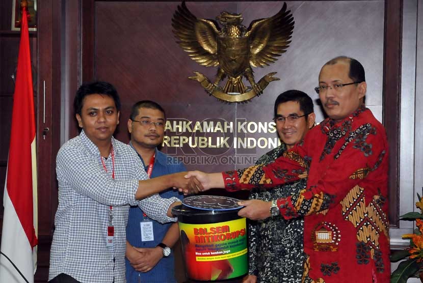  Aktivis yang tergabung dalam Masyarakat Sipil Anti Korupsi memberikan Balsem Anti Korupsi kepada Sekjen MK Janedri M Gaffar (kanan) disaksikan Ketua MK Hamdan Zoelva (kedua kanan) di gedung Mahkamah Konstitusi, Jakarta, Jumat (13/12).   (Republika/Prayogi