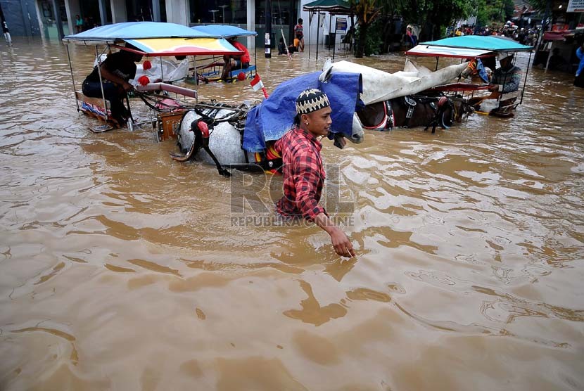 Aktivitas warga di Jalan KH Abdullah Syafei yang tergenang banjir akibat meluapnya Kali Ciliwung di Kampung Melayu, Jakarta, Sabtu (18/1). (Republika/Prayogi)