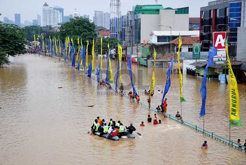 Aktivitas warga di Jalan KH Abdullah Syafei yang tergenang banjir akibat meluapnya Kali Ciliwung di Kampung Melayu, Jakarta, Sabtu (18/1). (Republika/Prayogi)
