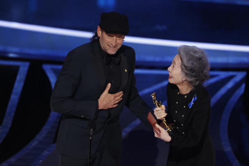 Aktor AS Troy Kotsur didampingi pembawa acara yang juga aktris asal Korea Selatan, Youn Yuh-jung, menerima piala Oscar untuk kategori Aktor Pemeran Pendukung Terbaik, di Dolby Theatre, Hollywood, AS, Ahad (27/3/2022) waktu setempat. Kotsur meraih penghargaan itu lewat perannya di film CODA.