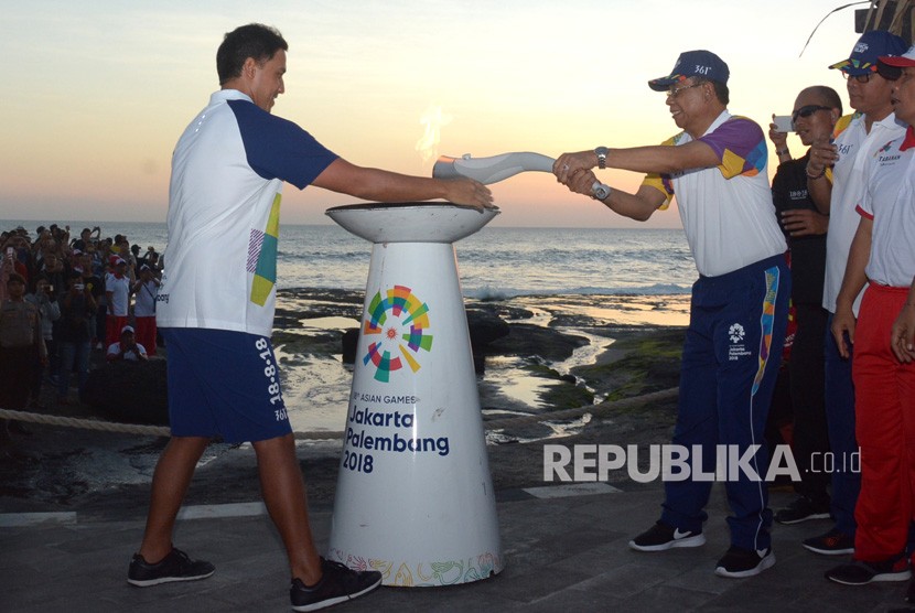 Celebrity Hamish Daud (left) handed over Asian Games 2018 torch to Tabanan District Secretary, Nyoman Wirna Ariwangsa at Tanah Lot, Tabanan, Bali, Monday (July 23). 