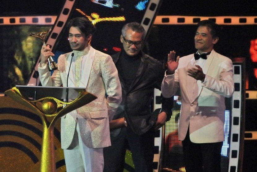 Aktor Reza Rahadian (kiri) memperlihatkan Piala Citra untuk kategori pemeran utama pria terbaik dalam film Habibie & Ainun, pada Malam Penganugerahan Festival Film Indonesia (FFI) 2013 di Marina Convention Centre (MCC) Semarang, Jateng, Sabtu (7/12) malam