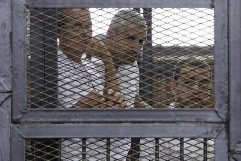Jurnalis Al Jazeera (kiri ke kanan) Peter Greste, Mohammed Fahmy dan Baher Mohamed di balik jeruji besi di pengadilan Kairo, Mesir, 1 Juni 2014.
