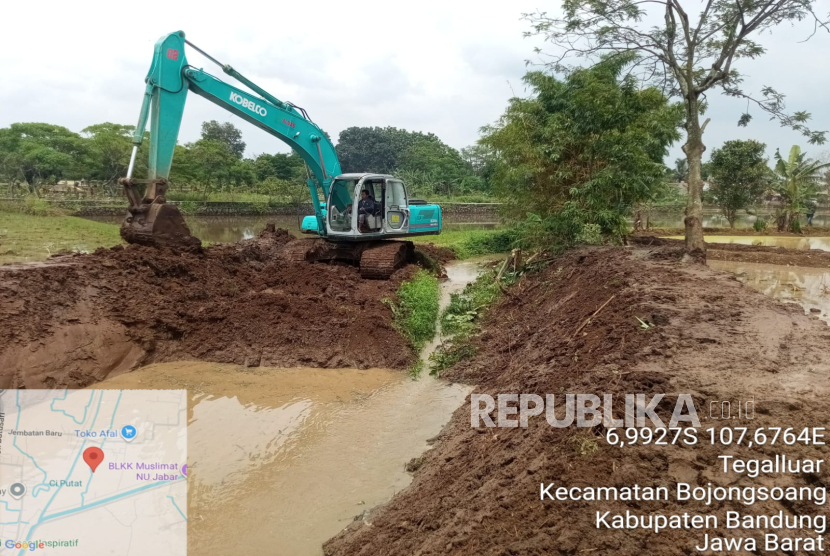 Alat berat back hoe terlihat melakukan pengerjaan dengan cara memperlebar dan memperdalam aliran sungai Ciputat.