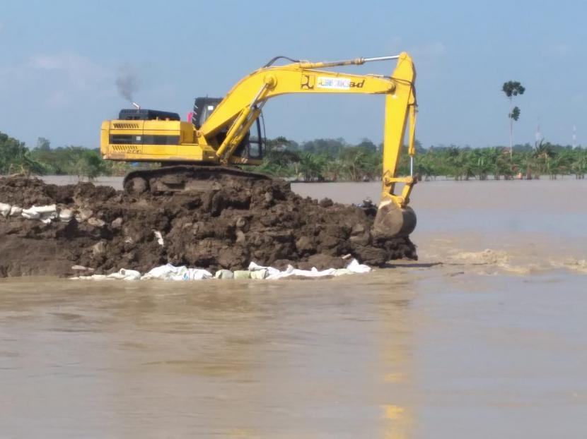 Alat berat didatangkan untuk memperbaiki tanggul sungai Cipanas yang jebol di Blok Widara, Desa Puntang, Kecamatan Losarang, Kabupaten Indramayu, Sabtu (27/2). 