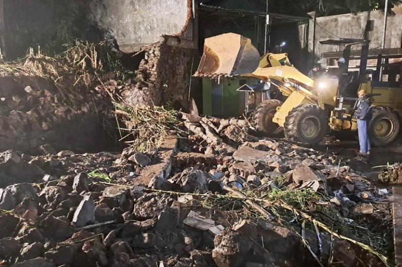 Alat berat dikerahkan untuk membersihkan material sisa reruntuhan dinding pembatas sepanjang 30 meter yang roboh di Jalan Damin 14, Desa Beji, Kecamatan Junrejo, Kota Batu, Jawa Timur, Senin (29/1/2024).