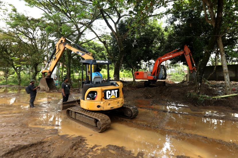 Alat berat membersihkan material lumpur yang menutupi jalan di Sukorambi, Kaliwates, Jember, Jawa Timur. Pengerahan alat berat dan kendaraan taktis 
