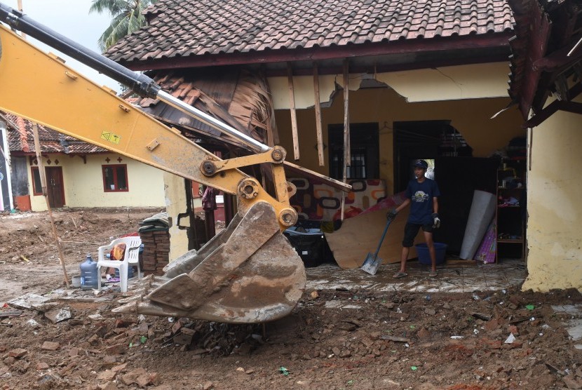 Alat berat membersihkan puing yang hancur akibat tsunami.