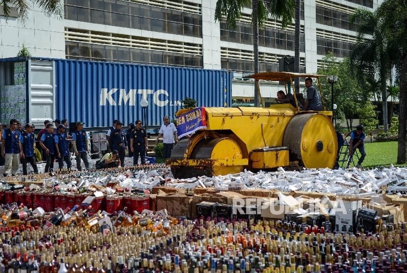 Alat berat memusnahkan ribuan minuman keras dan rokok hasil sitaan bea cukai di halaman gedung Bea Cukai, Jakarta Timur, Jumat (23/12). 