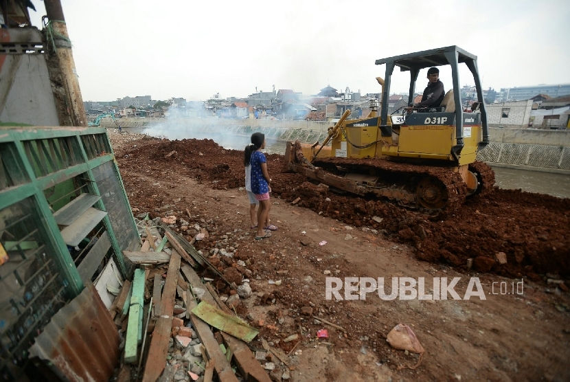 Alat berat meratakan tanah sebagai tahap awal normalisasi di Bantaran kali Ciliwung, Bukit Duri, Jakarta, Selasa (4/10).