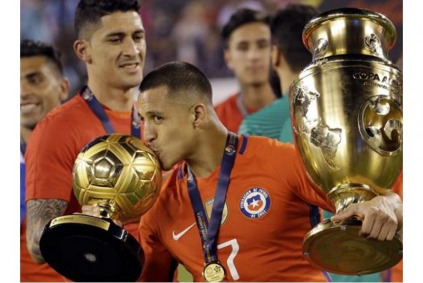 Alexis Sanchez mencium trofi pemain terbaik Copa America Centenario 2016.