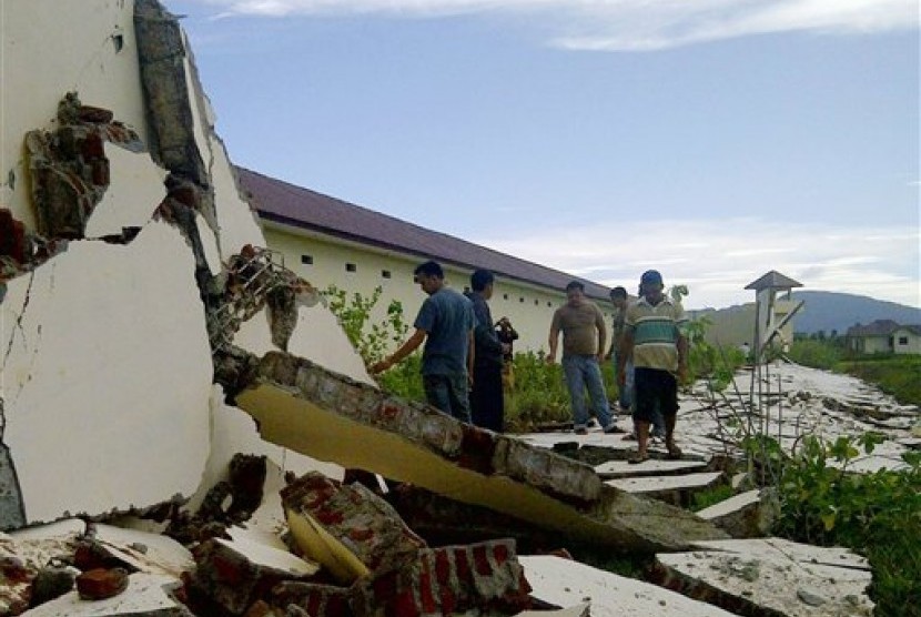 An Acehnese man makes his way under the collapsed roof of a building after it was destroyed by an earthquake in Ketol, Central Aceh, Indonesia, early Wednesday, July 3, 2013. 