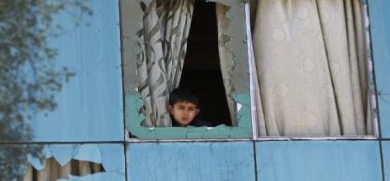 An Afghan boy looks out from a broken window during a demonstration in Jalalabad province February 22, 2012. Gunfire wounded at least 26 people during fresh protests in several cities across Afghanistan over the burning of copies of the Koran, Islam's holy